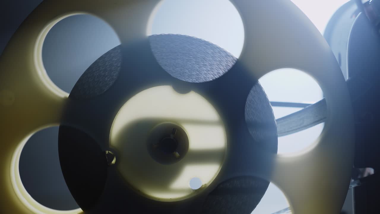 회전하는 필름 릴과 빛 광선으로 된 오래된 영화 프로젝터