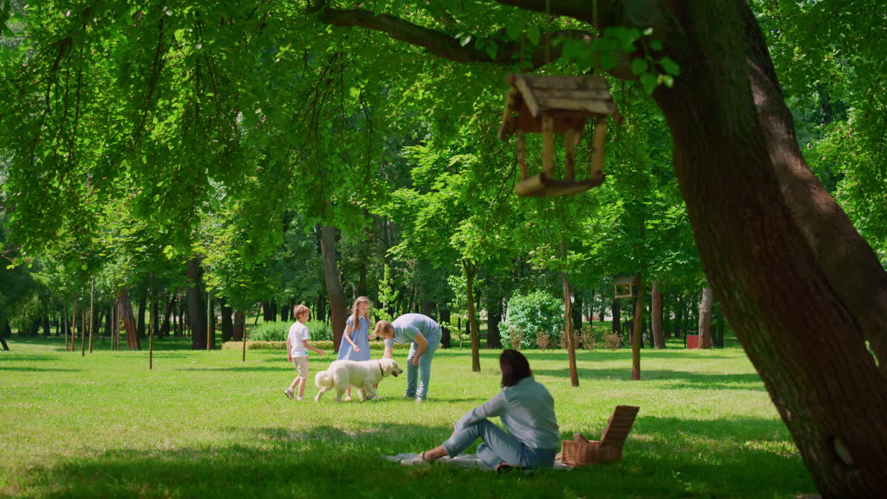 молодая семья проводит свободное время с собакой на открытом воздухе. счастливый пикник в зеленом парке.