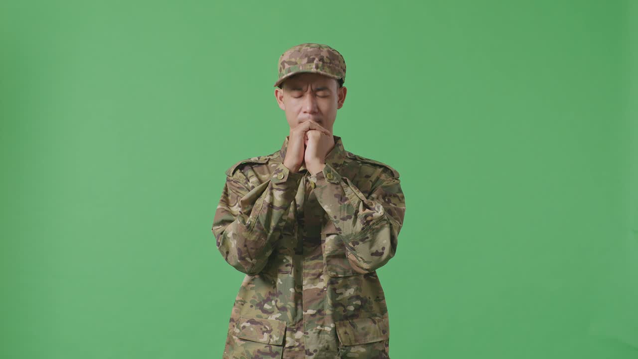 Asian Man Army Soldier Uniform Praying In The Green Screen Background Studio