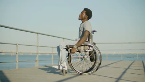 happy black man in wheelchair having fun at seafront