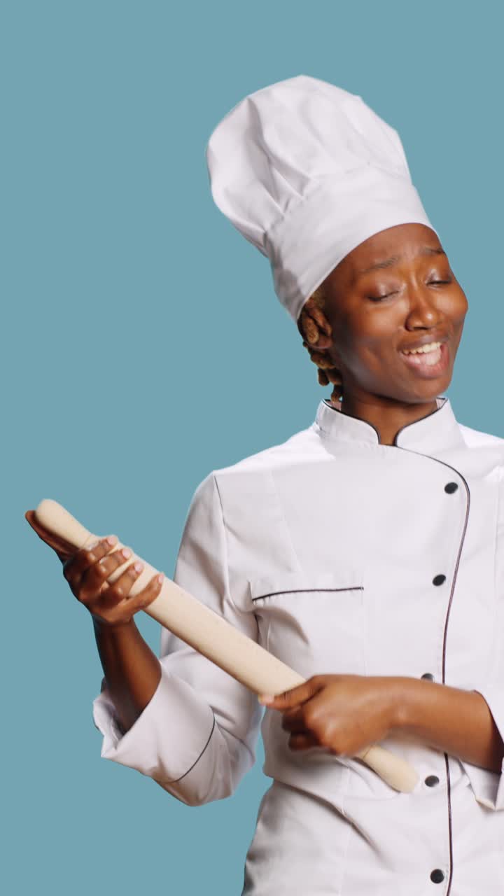 Video verticale: chef allegro e divertente che gioca con un matterello e canta