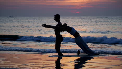 couple practicing yoga at sunset on a beach