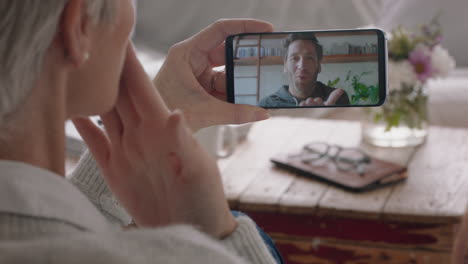 mujer madura teniendo video chat usando un teléfono inteligente hablando con su hijo en la pantalla del teléfono móvil sonriendo disfrutando de la conversación compartiendo estilo de vida con la familia 4k