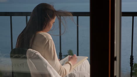 woman drawing on a balcony with a lake view