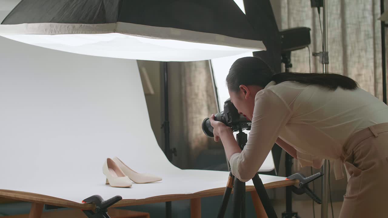 아시아 여성 사진작가가 가정 스튜디오에서 여성 신발의 사진을 찍고 있습니다.