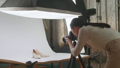 fotógrafa asiática tomando fotos de zapatos femeninos en su estudio casero