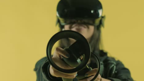 young woman playing with controllers and wonders how amazing in the vr headset. virtual reality helmet on the yellow background.