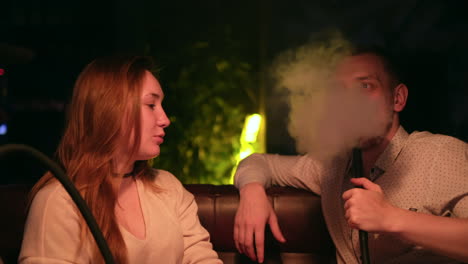 pareja relajándose con narguile en un club nocturno