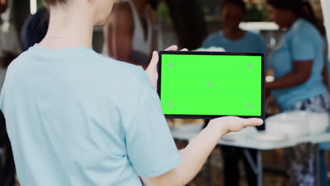 tableta con pantalla verde sostenida por una mujer