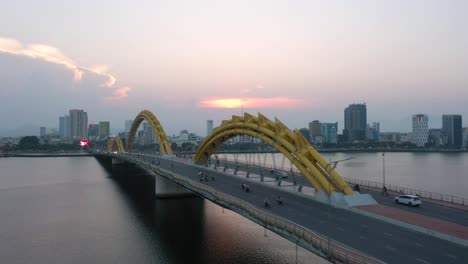 amazing colorful wide aerial shot of iconic dragon bridge cau rong, traffic and city skyline during sunset in danang, vietnam