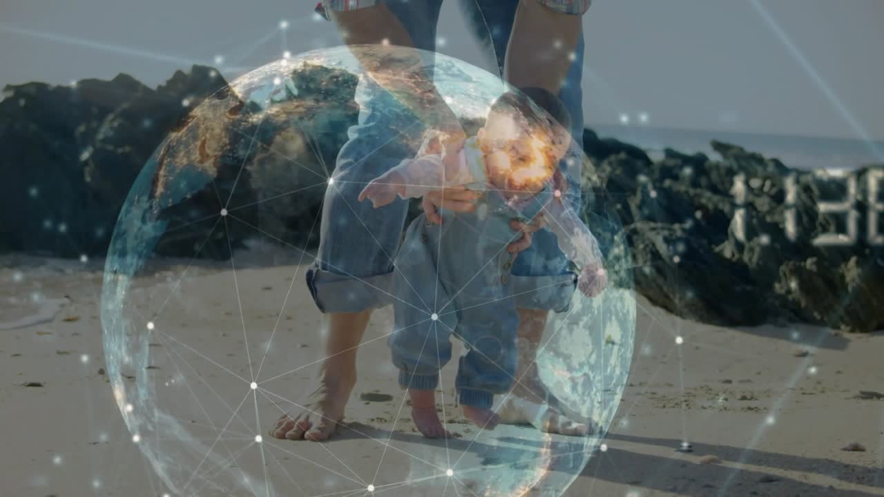 Parent placing infant feet on beach guiding standing while tech globe growing around child