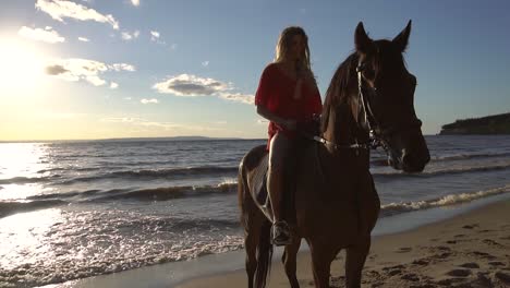 mujer montando a caballo en la playa del atardecer