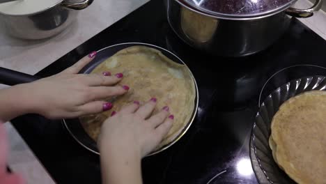 The-process-of-cooking-homemade-pancakes.-Woman-turns-pancake-in-a-frying-pan