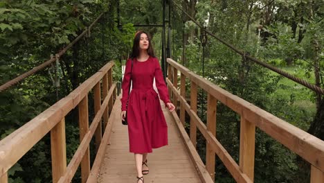 girl in red smiling walks across the bridge