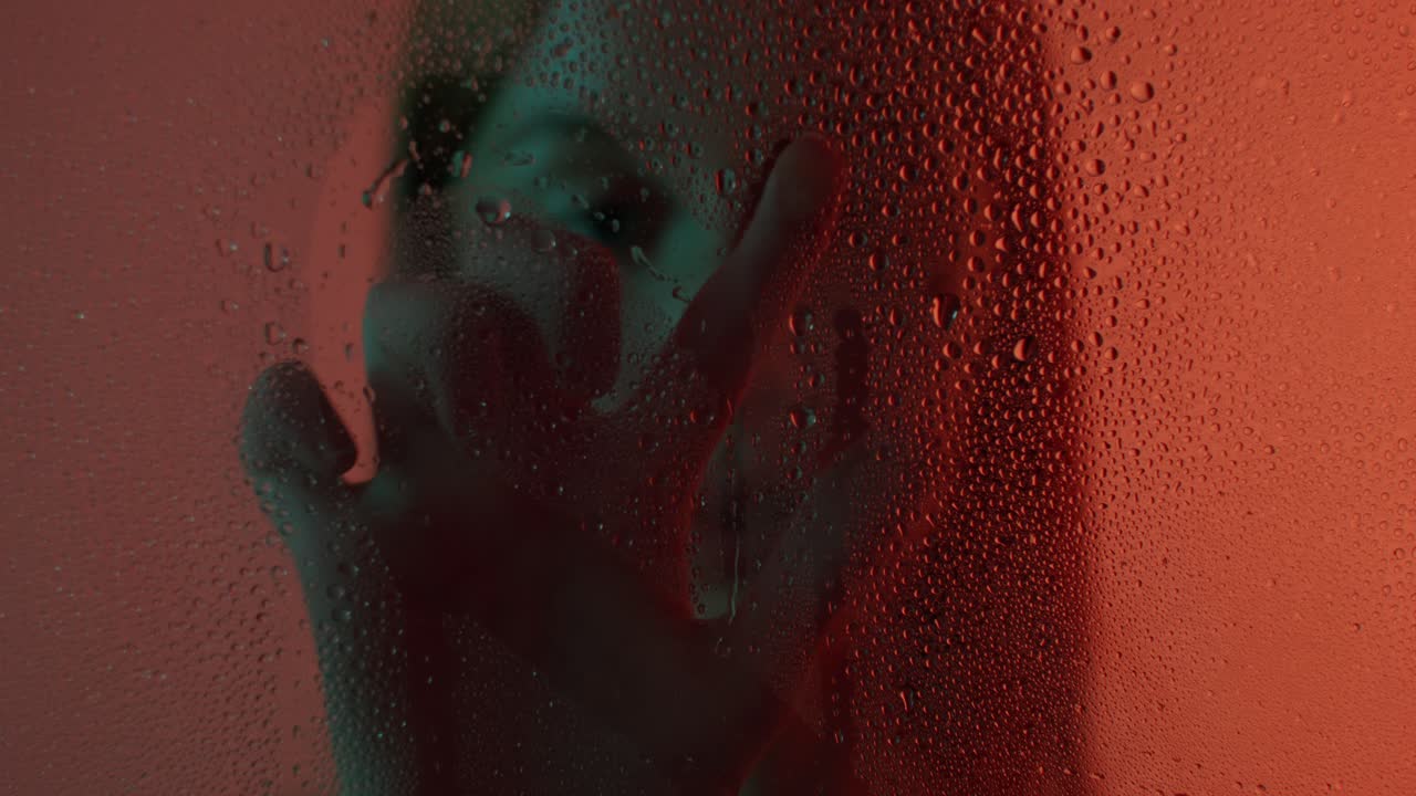 retrato abstracto de una mujer a través de una ventana cubierta de gotas de agua