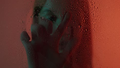 retrato abstracto de una mujer a través de una ventana cubierta de gotas de agua