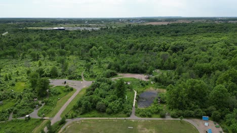 Descending-pedestal-shot-of-soccer-field-near-large-thick-lush-forest