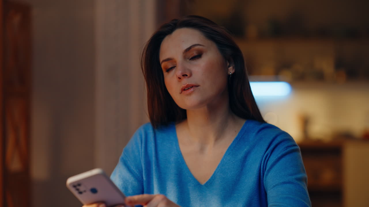 Bored lady scrolling smartphone sitting evening home closeup. Serious brunette