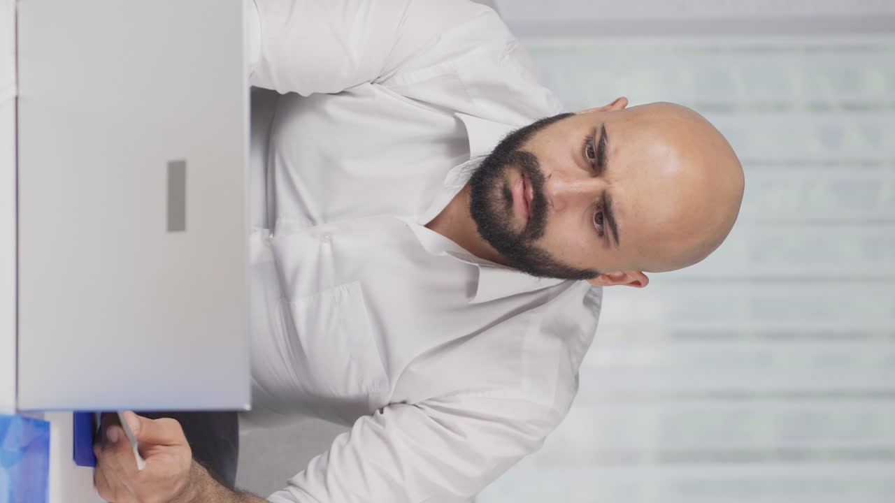 Vertical video of Home office worker man getting bad news from camera.