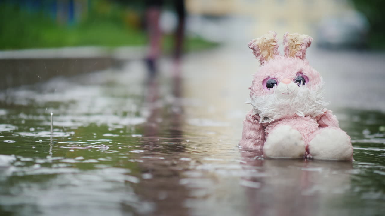 un conejito de peluche húmedo está sentado en un charco bajo la lluvia el transeúnte pasa por la indiferencia y la frialdad con