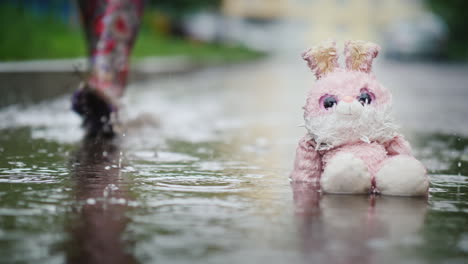 Ein-Feuchter-Plüschhase-Sitzt-In-Einer-Pfütze-Im-Regen-Passant-Geht-An-Gleichgültigkeit-Und-Kälte-Vorbei