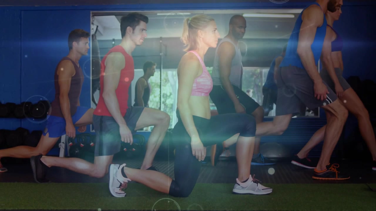 Fitness group stepping into lunges on instructor cue for training, lens flares accenting movement