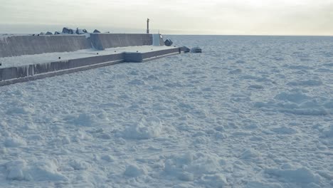 Aerial-Along-Frozen-Drift-Sea-Ice-At-Sawaki-Port,-Hokkaido-Beside-Breakwater-Wall