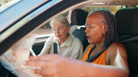 dos amigas mayores confundidas en un viaje de un día conduciendo en un coche leyendo un mapa buscando perderse