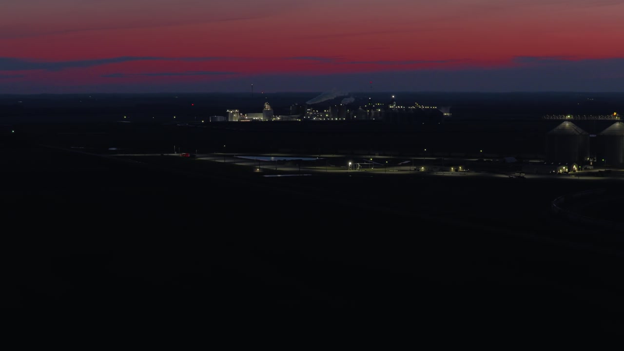 紺碧の夜空の下、果てしない暗い平野に加工工場がぼんやりと輝き、夜通し稼働する産業の静かで孤独な雰囲気を醸し出している。