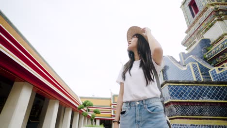 cheerful young asian woman traveling at wat pho temple in bangkok, thailand.