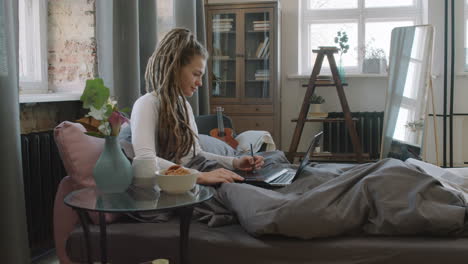 digital designer working in bed while having breakfast