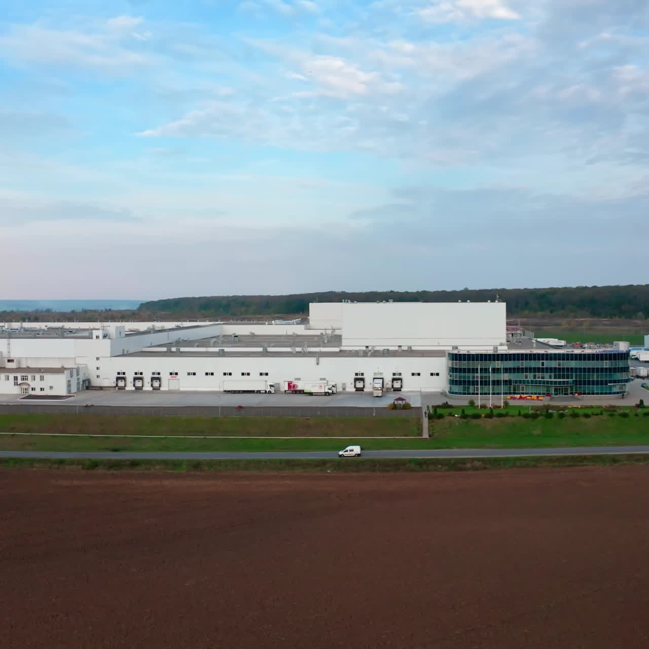 Contemporary farm on nature background. White architecture of industrial plant near the highway. Innovative factory on field. Motion camera to the right.