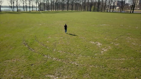 Luftdrohnenaufnahme-Des-Vorwärtsfliegens,-Der-Der-Erwachsenen-Frau-In-Einem-Schwarzen-T-Shirt-Folgt,-Die-Im-Park-Spazieren-Geht