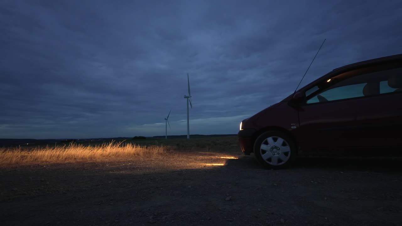 풍력 터빈 필드 타임 스 낮부터 밤까지, 자동차 조명이 길을 조명합니다.