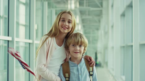 Foto-De-Retrato-De-Los-Niños-Felices,-Niña-Y-Niño,-De-Pie-En-El-Aeropuerto-Y-Sonriendo-A-La-Cámara-Con-La-Bandera-Americana-1