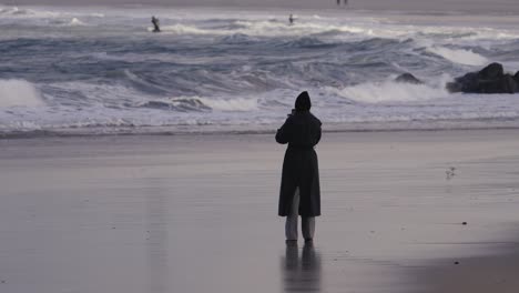 Girl-on-beach-watching-kitesurfing-on-ocean-waves,-static-view,-copyspace