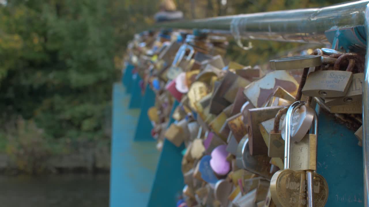 Close up lots of padlocks connected to railings on bridge over water close up