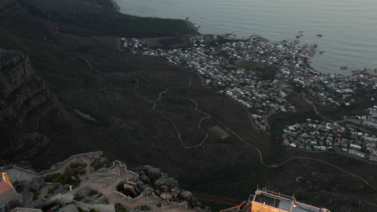 Aerial tilt down of Cable Station Table Mountain with in the background Campsbay with sunrise in Cape Town South Africa