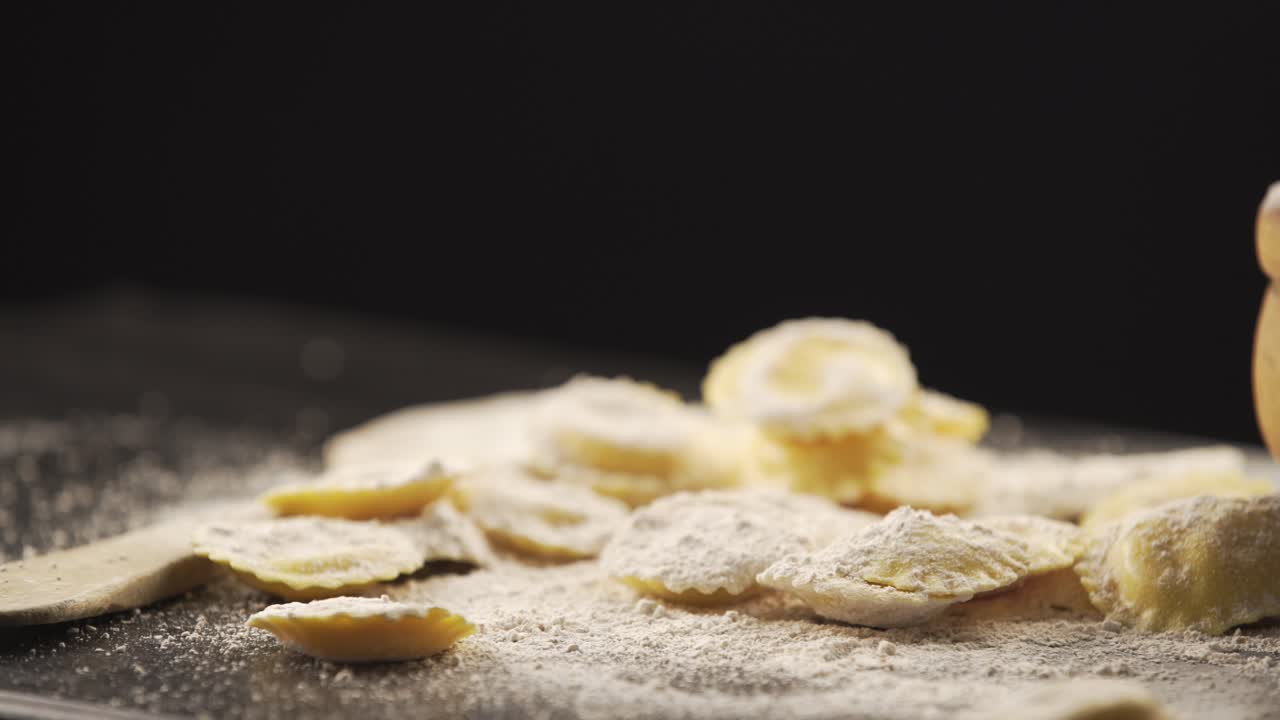 Tasty raw ravioli with flour and basil on wood table