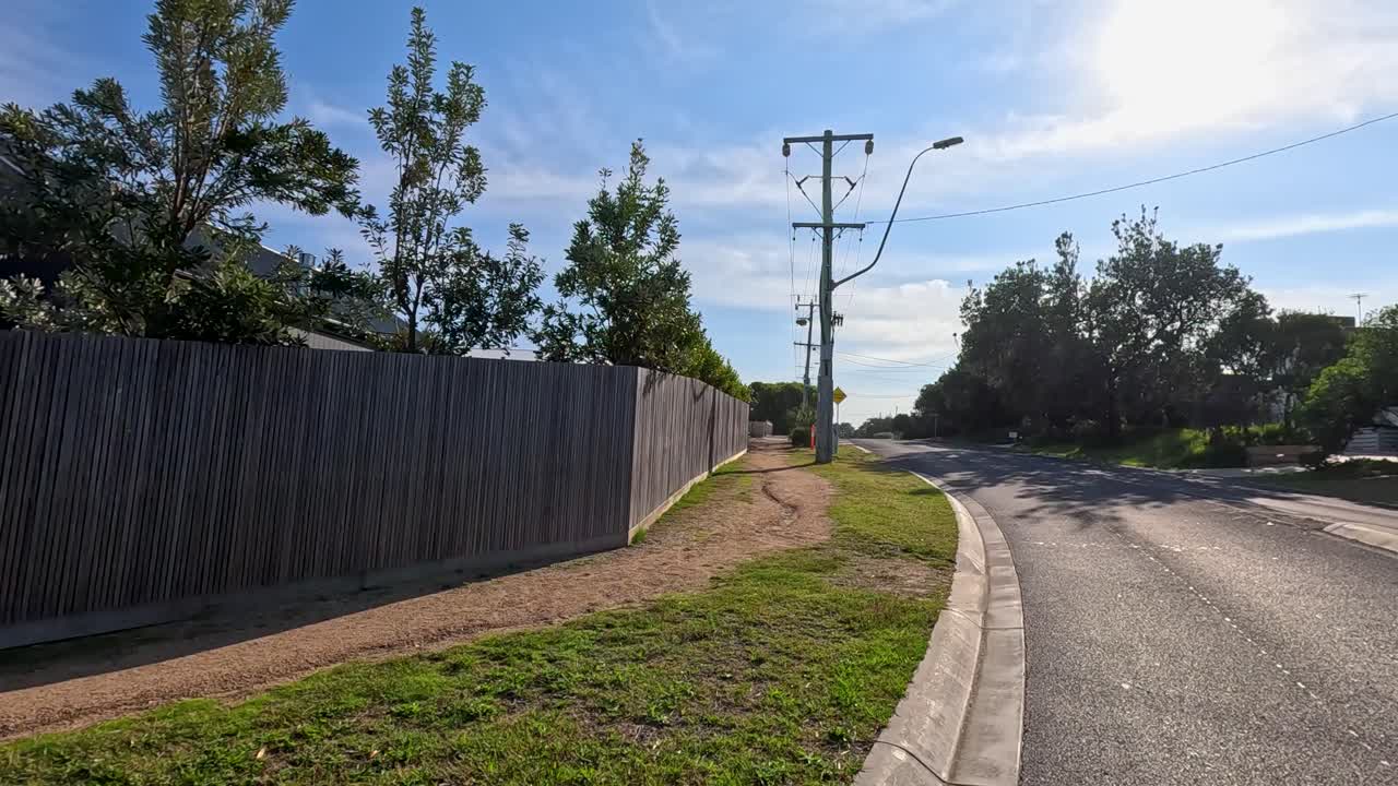 A serene drive through Point Lonsdale's suburban streets, showcasing clear skies, residential homes, and natural greenery