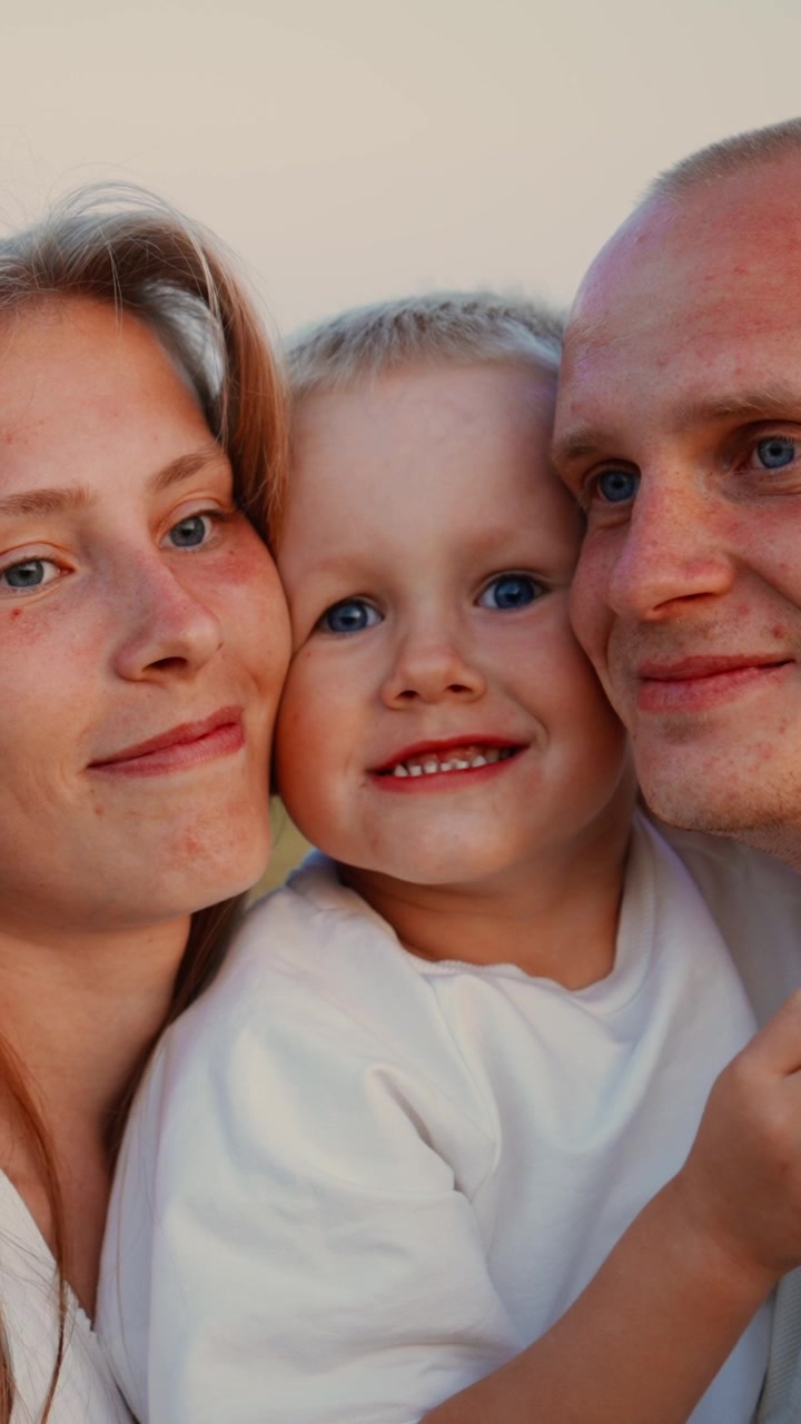 Glad ung familie omfavner hinanden udendørs ved solnedgang
