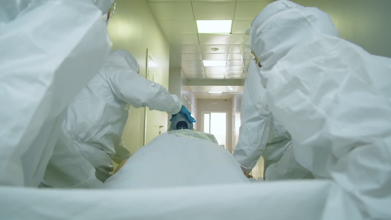 보호복 을 입은 의사 들 이 환자 를 기차 에 밀어 넣고 있다