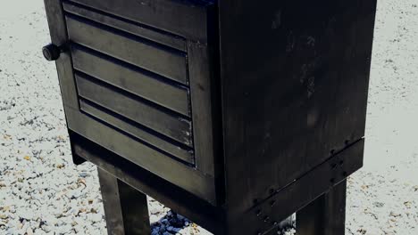 an old fashion newspaper box painted black without a newspaper