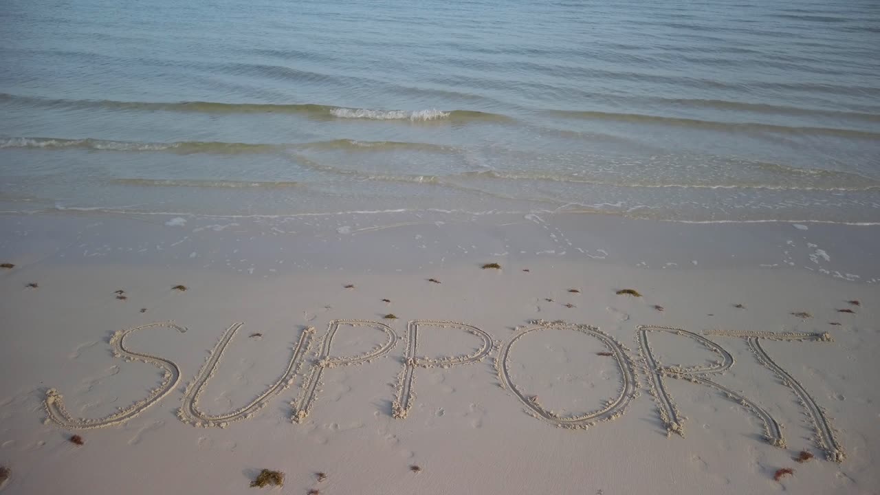 모래 위에 물이 찰싹 달라붙는 해변의 모래에 쓰여진 정적 지지 샷