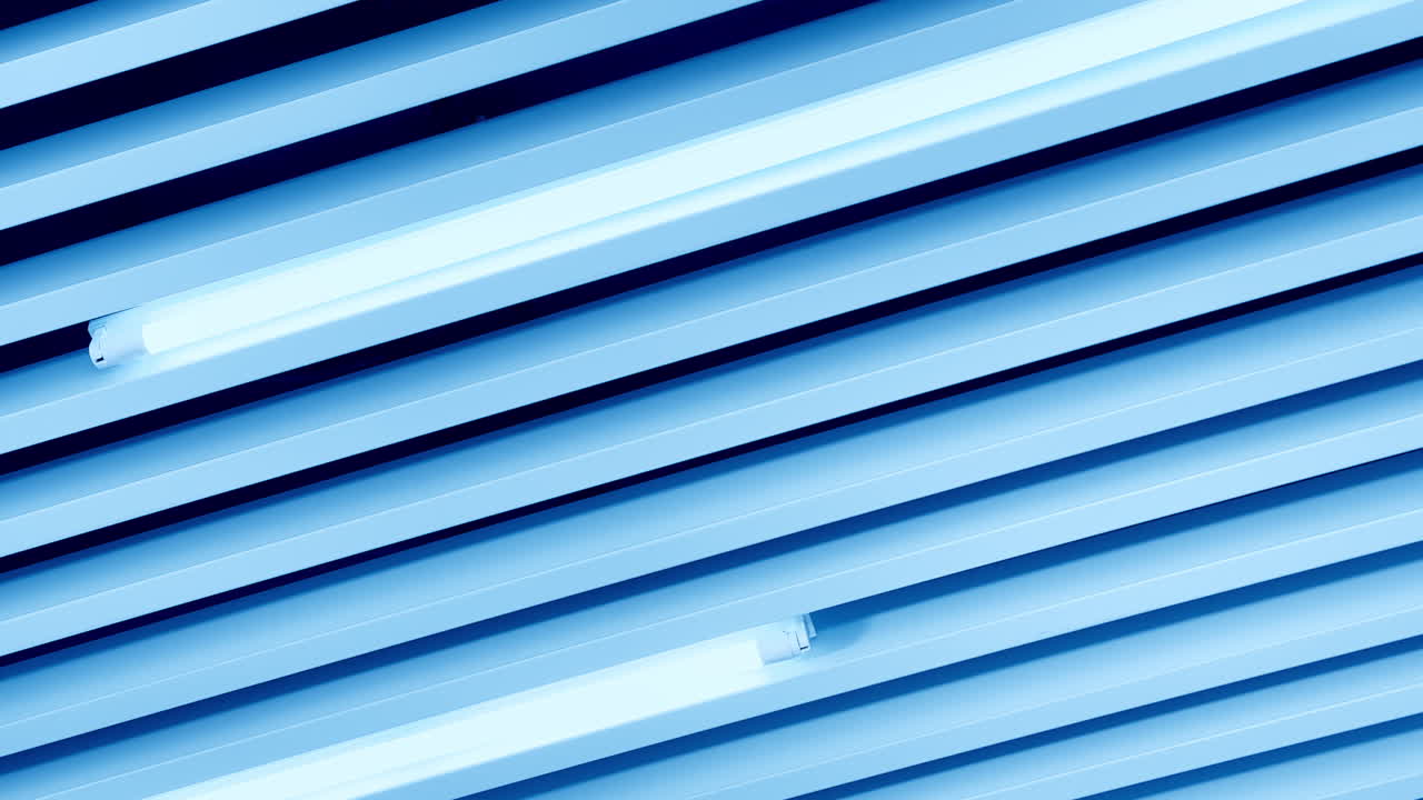 White light of long led lamps among the decorative panels on the ceiling. View from below.