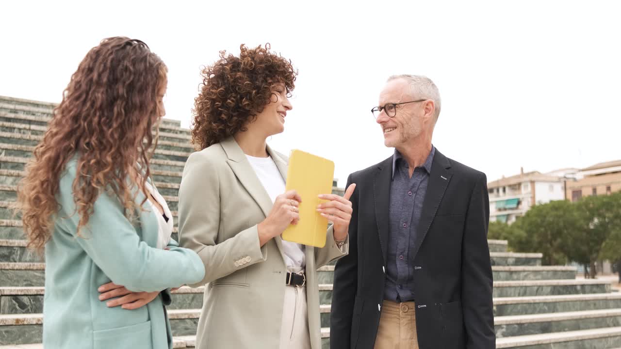 Smiling coworkers with tablet discussing project near steps