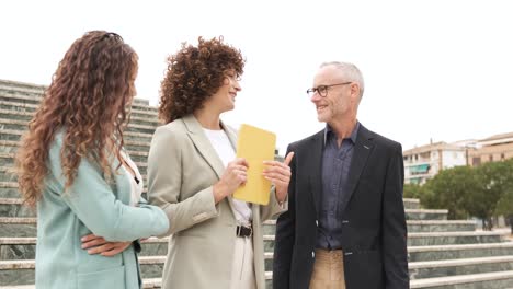 smiling coworkers with tablet discussing project near steps