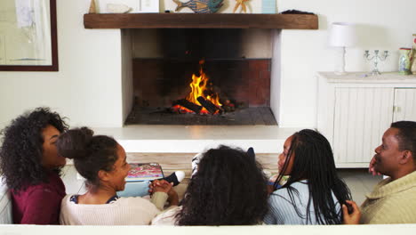 Familia-Sentada-En-Un-Sofá-En-El-Salón-Junto-A-La-Chimenea