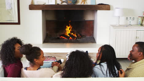 family sitting on sofa in lounge next to open fire