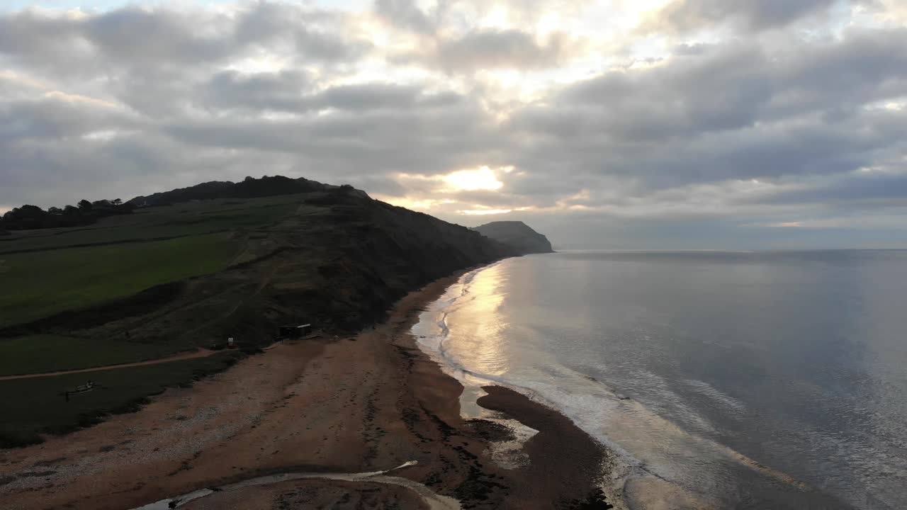 vista aérea de los acantilados a lo largo de la playa de charmouth durante el amanecer a través de las nubes